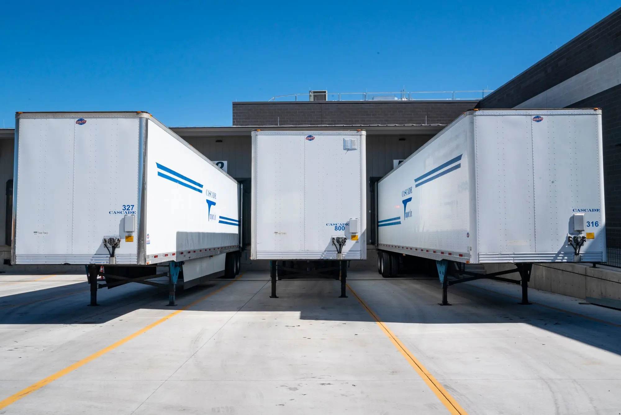 Three cargo trailers parked at an industrial shipping dock.